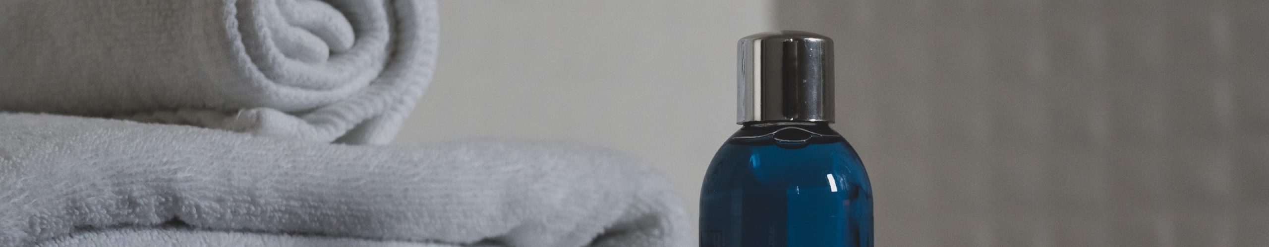 blue-glass-bottle-beside-white-towel-3872899